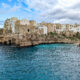 white and tan buildings on a cliff over a turquoise ocean