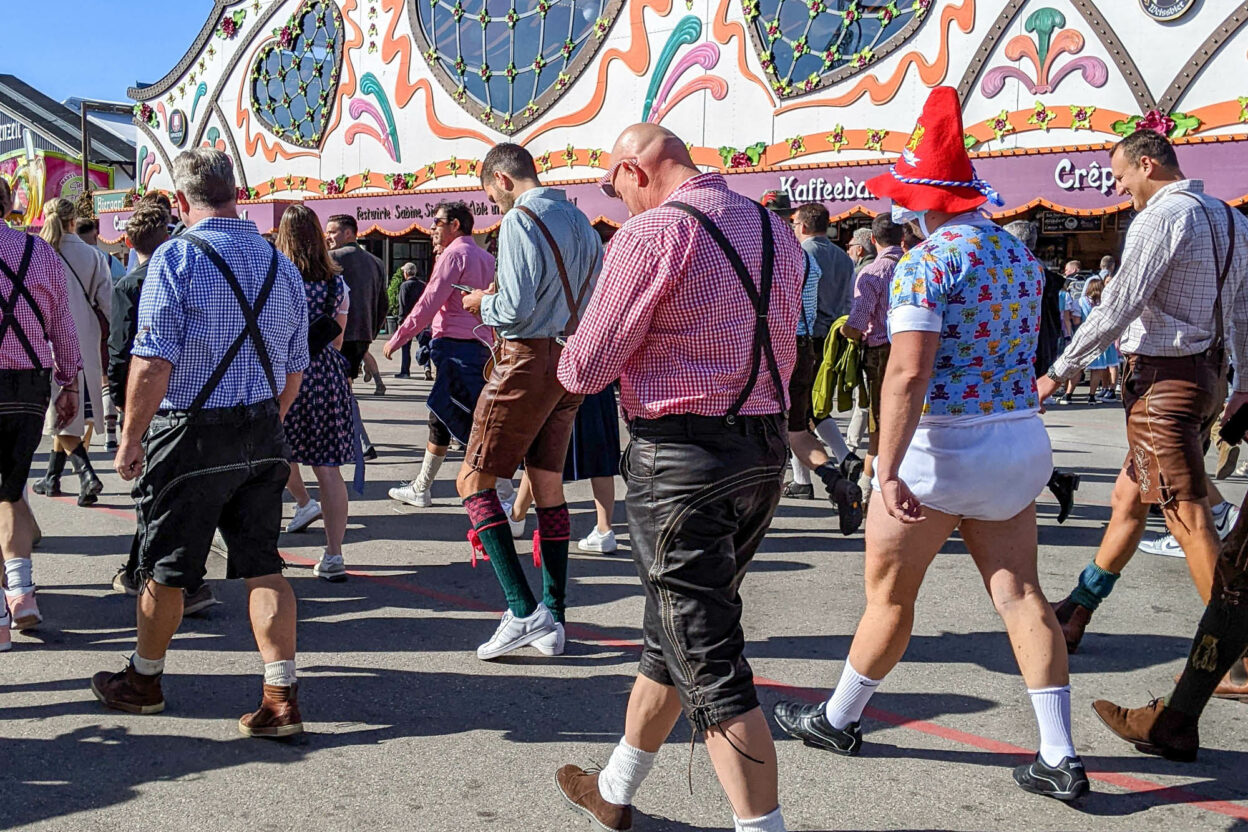 group of men walking through oktoberfest and one of them is wearing a diaper