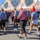 group of men walking through oktoberfest and one of them is wearing a diaper