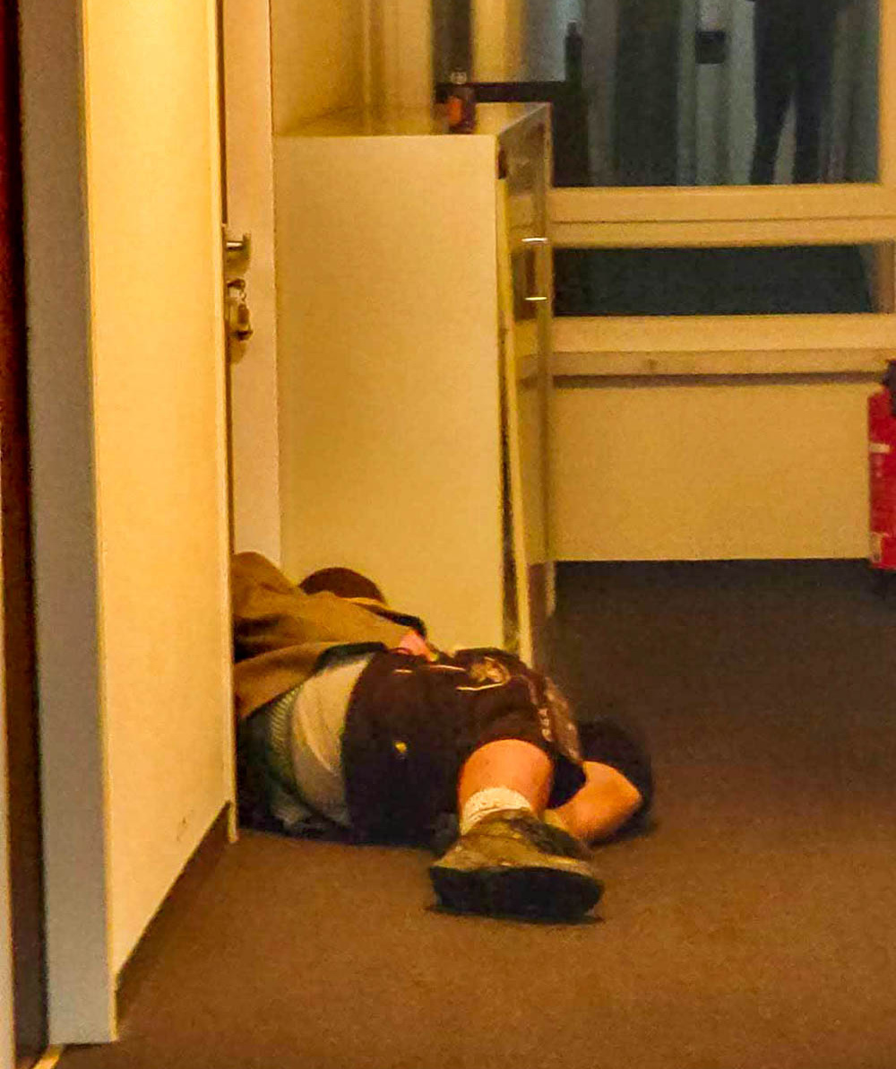 man sleeping in hotel hallway