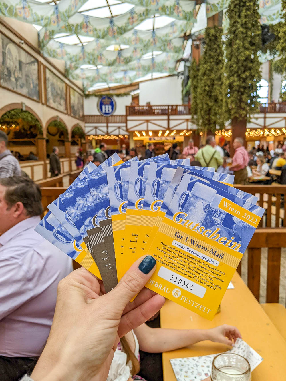 hand holding stack of blue and yellow paper vouchers inside a beer tent
