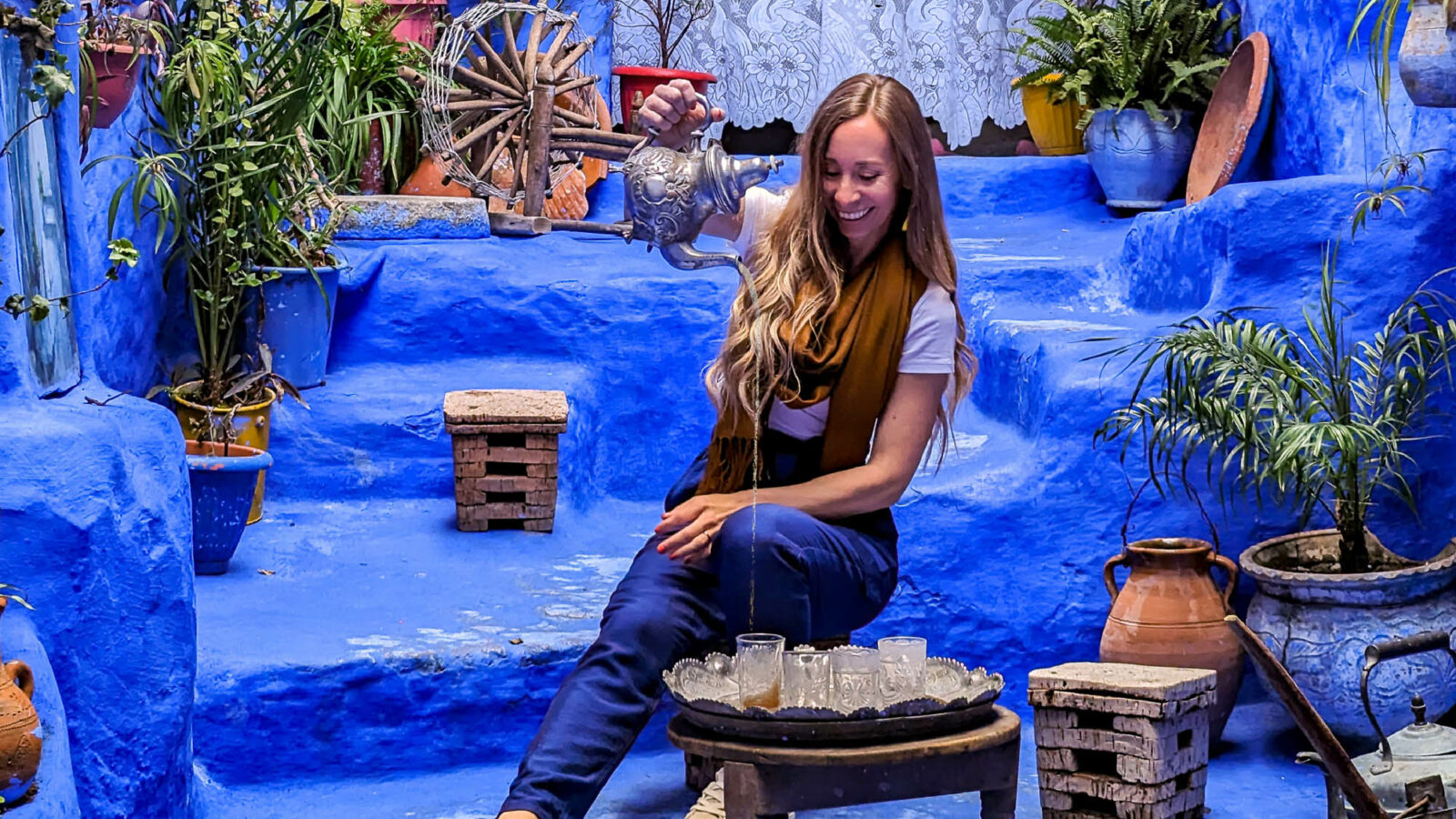 woman pouring tea in a blue courtyard