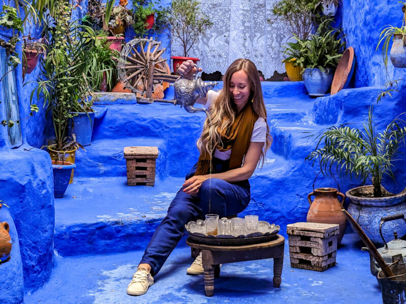 woman pouring tea in a blue courtyard