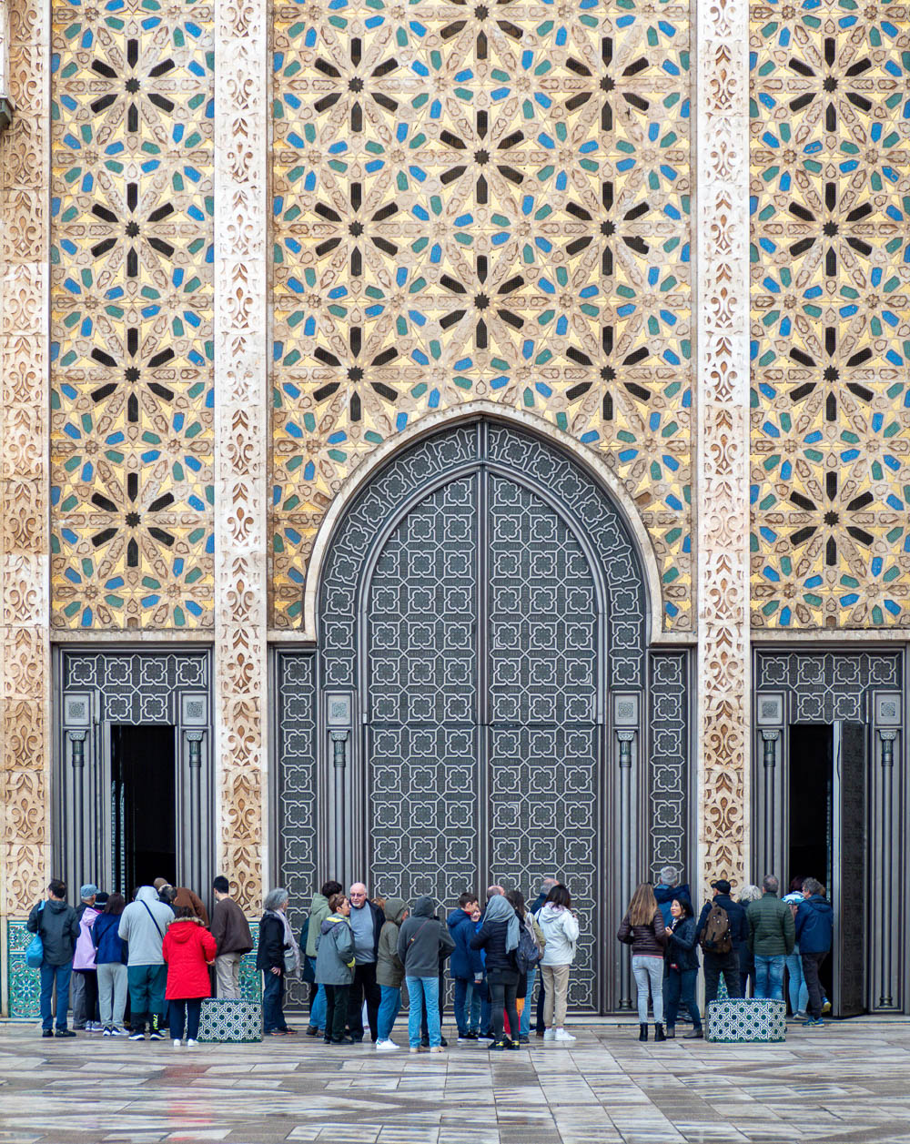 crowd of people standing in front of a large door in the rain