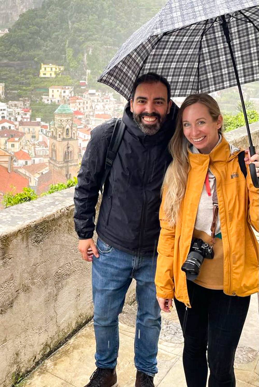 women in yellow rain jacket and man in black rain jacket under an umbrella above a city