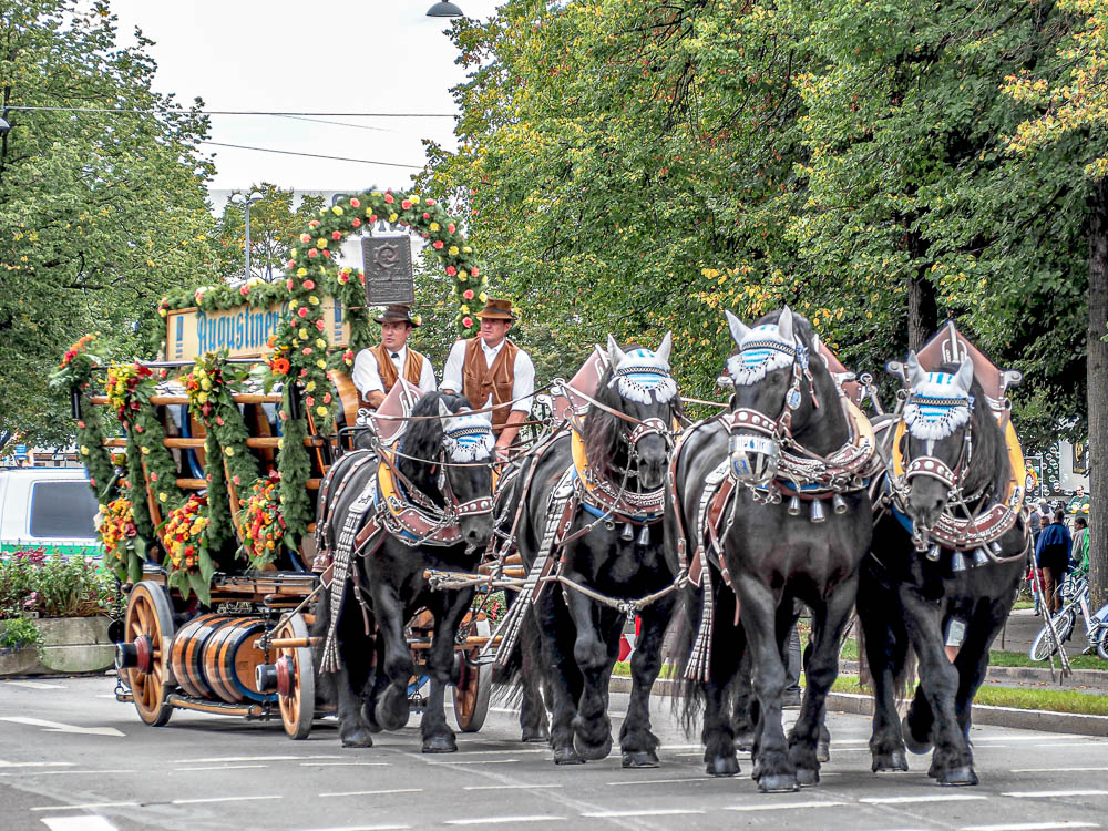 two men driving a horse-drawn beer carriage through town