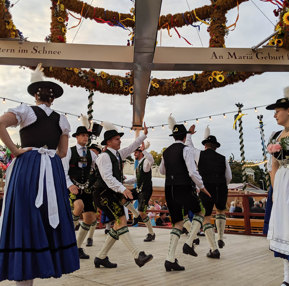 men and women in traditional bavarian clothing dancing outside