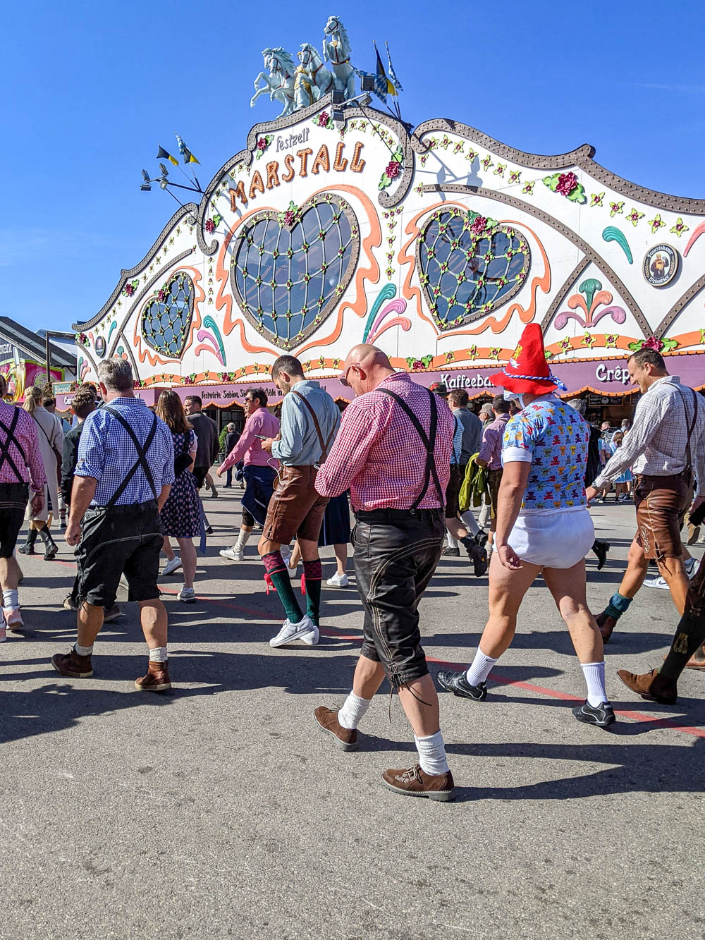 group of men walking through oktoberfest, one of them in a diaper for some reason