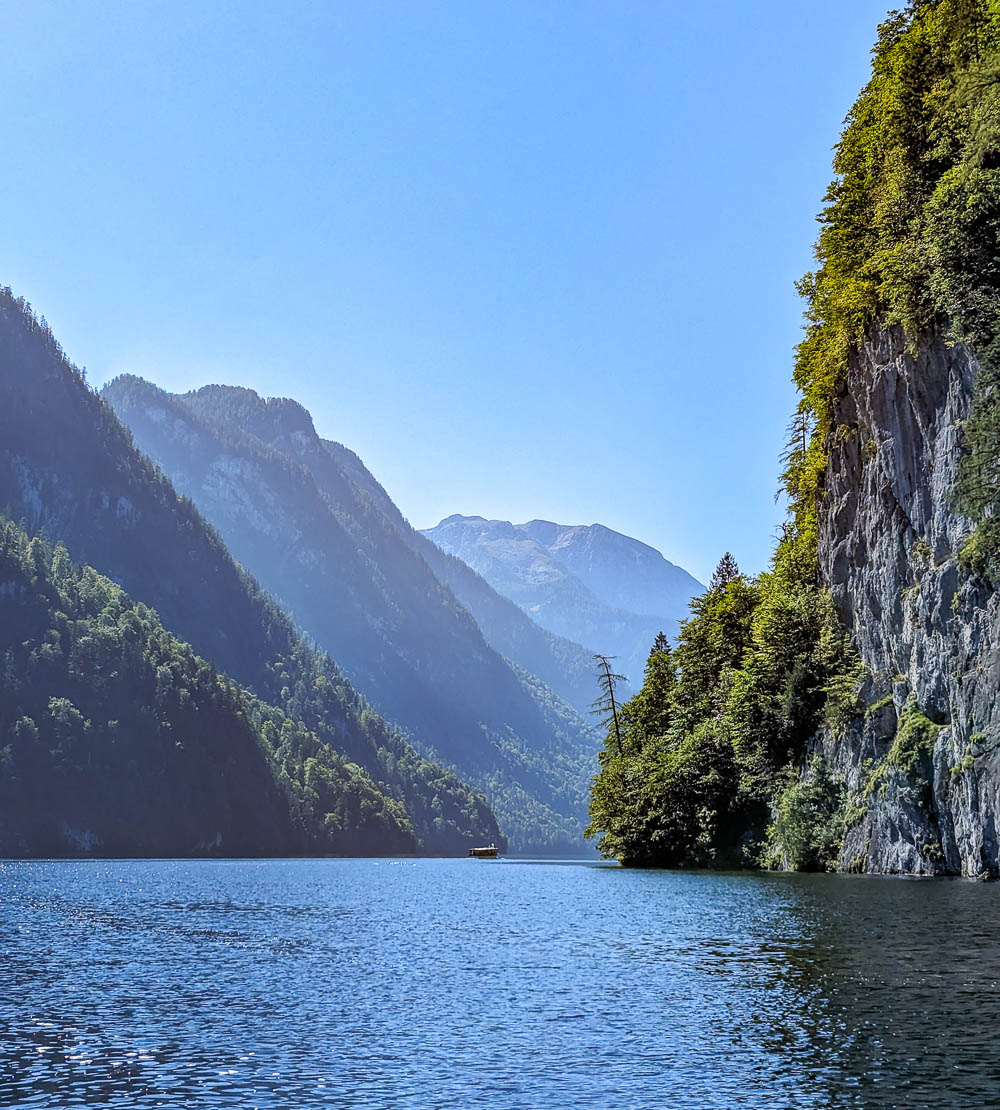 tiny boat on a huge lake surrounded by tall mountains on a sunny day