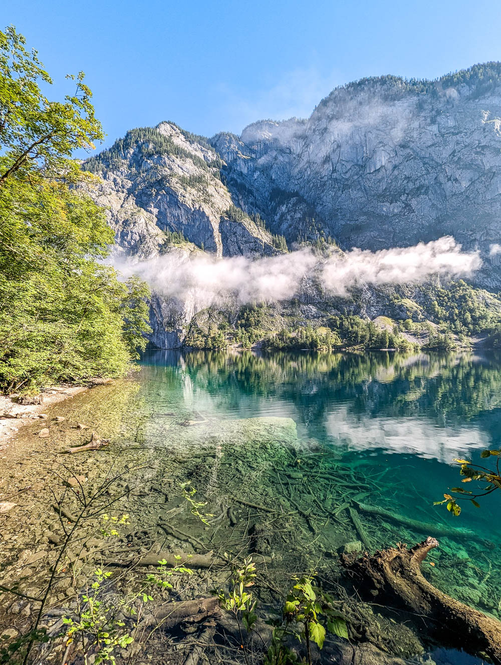 view of turquoise green lake next to a mountain under a cloud