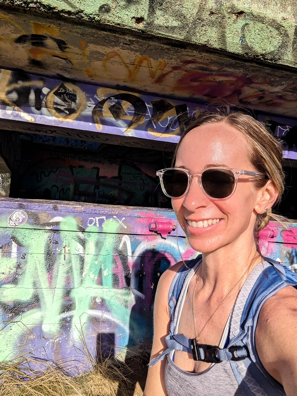 woman in sunglasses in front of a colorful spraypainted structure