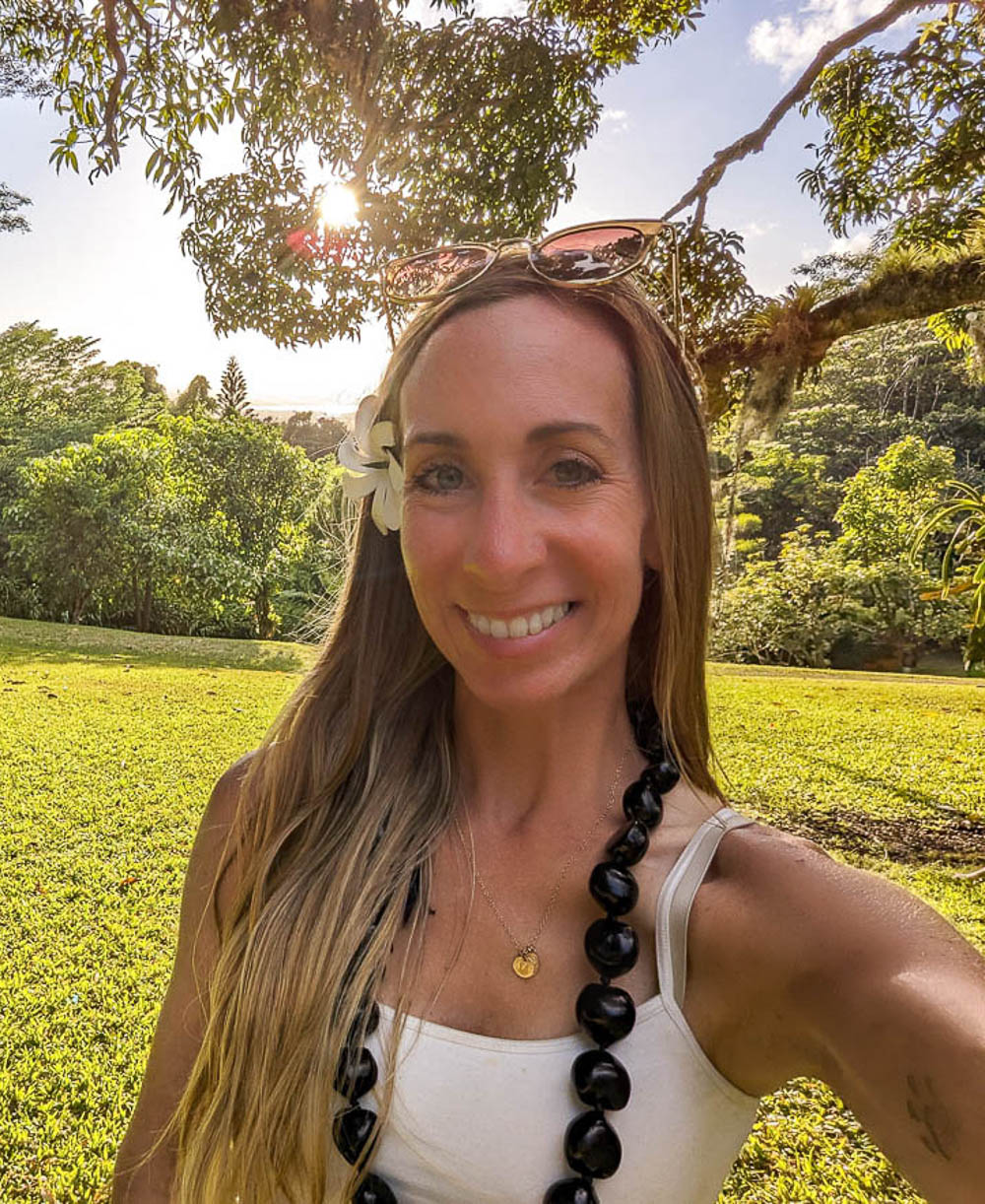 woman in white shirt with white flower behind her ear and a black shell lei