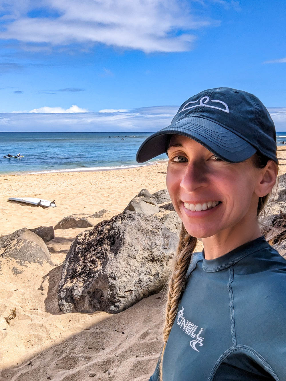 woman selfie on a beach next to a surfboard