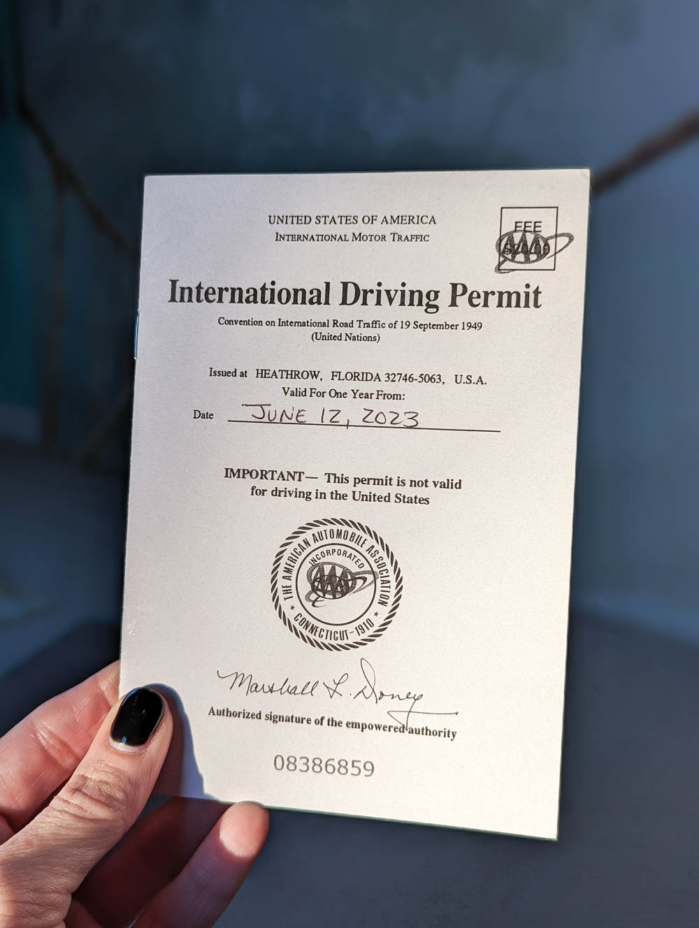 woman's hand holding a small document with International Driving Permit on it