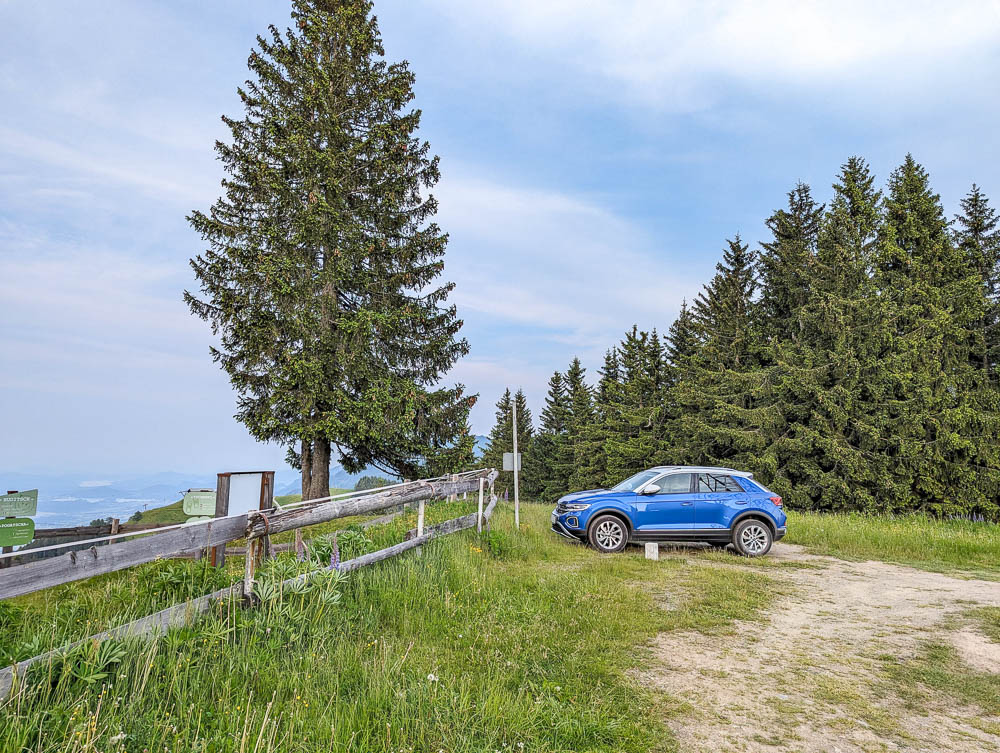blue car parked in the grass at the top of a mountain