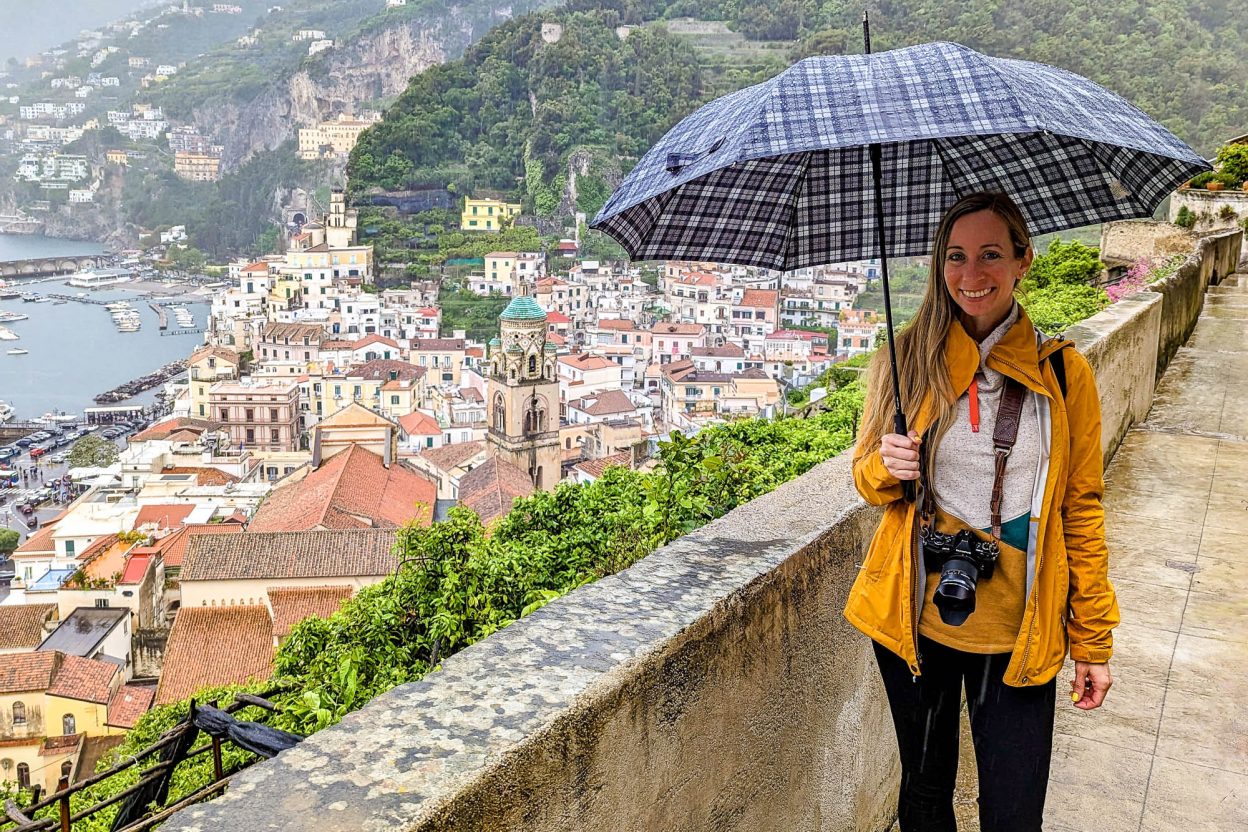 girl in yellow rain jacket over a city lookout holding an umbrella