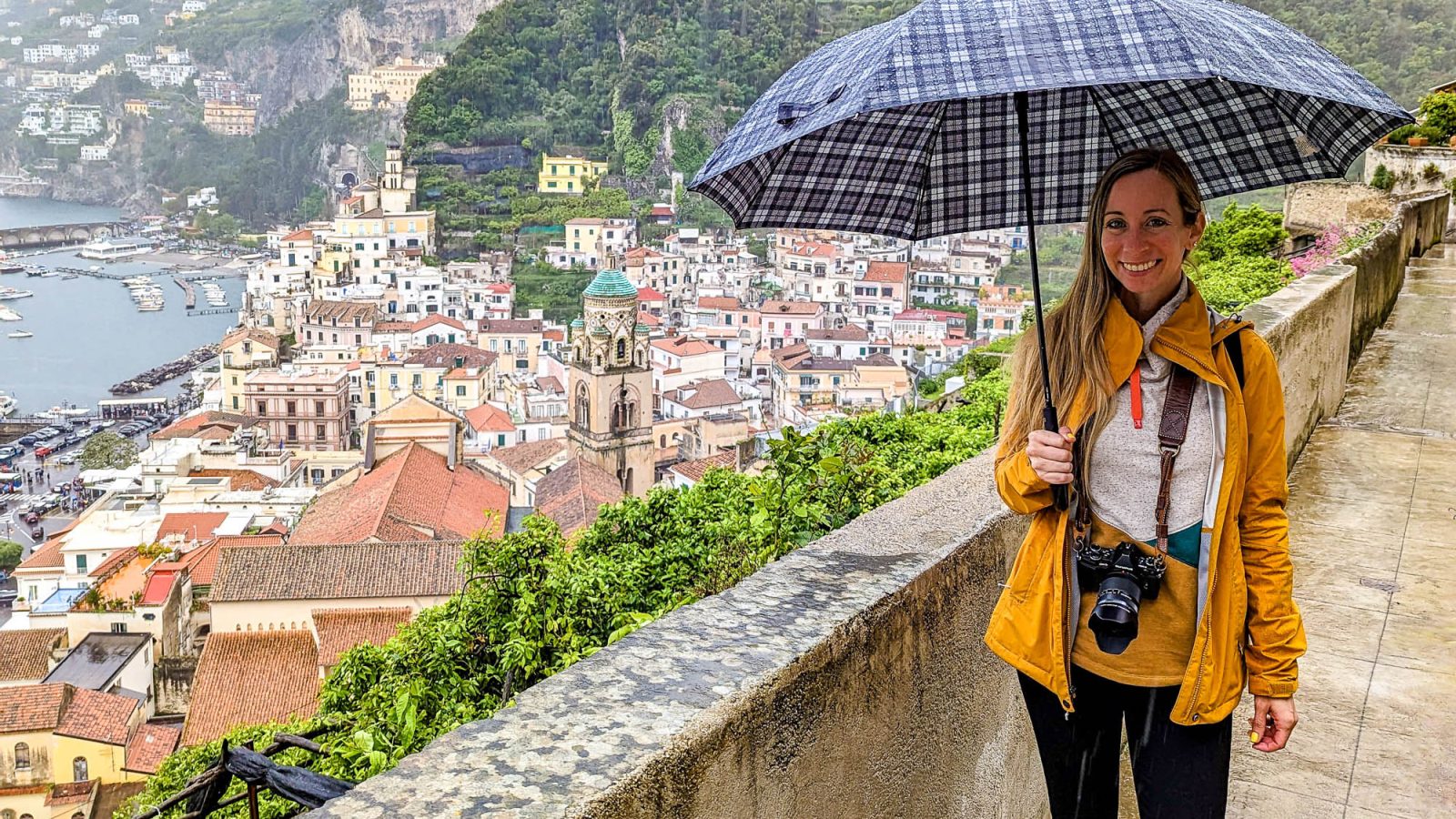 girl in yellow rain jacket over a city lookout holding an umbrella