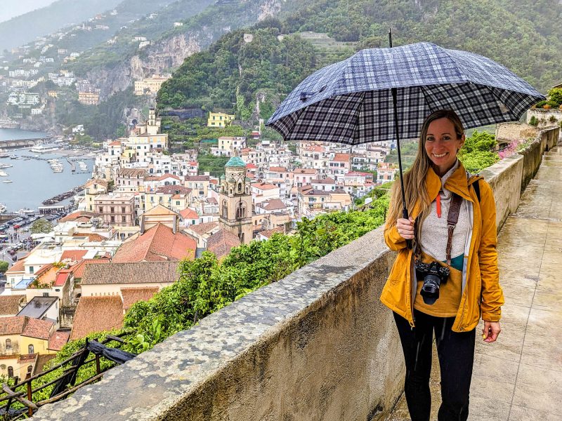 girl in yellow rain jacket over a city lookout holding an umbrella