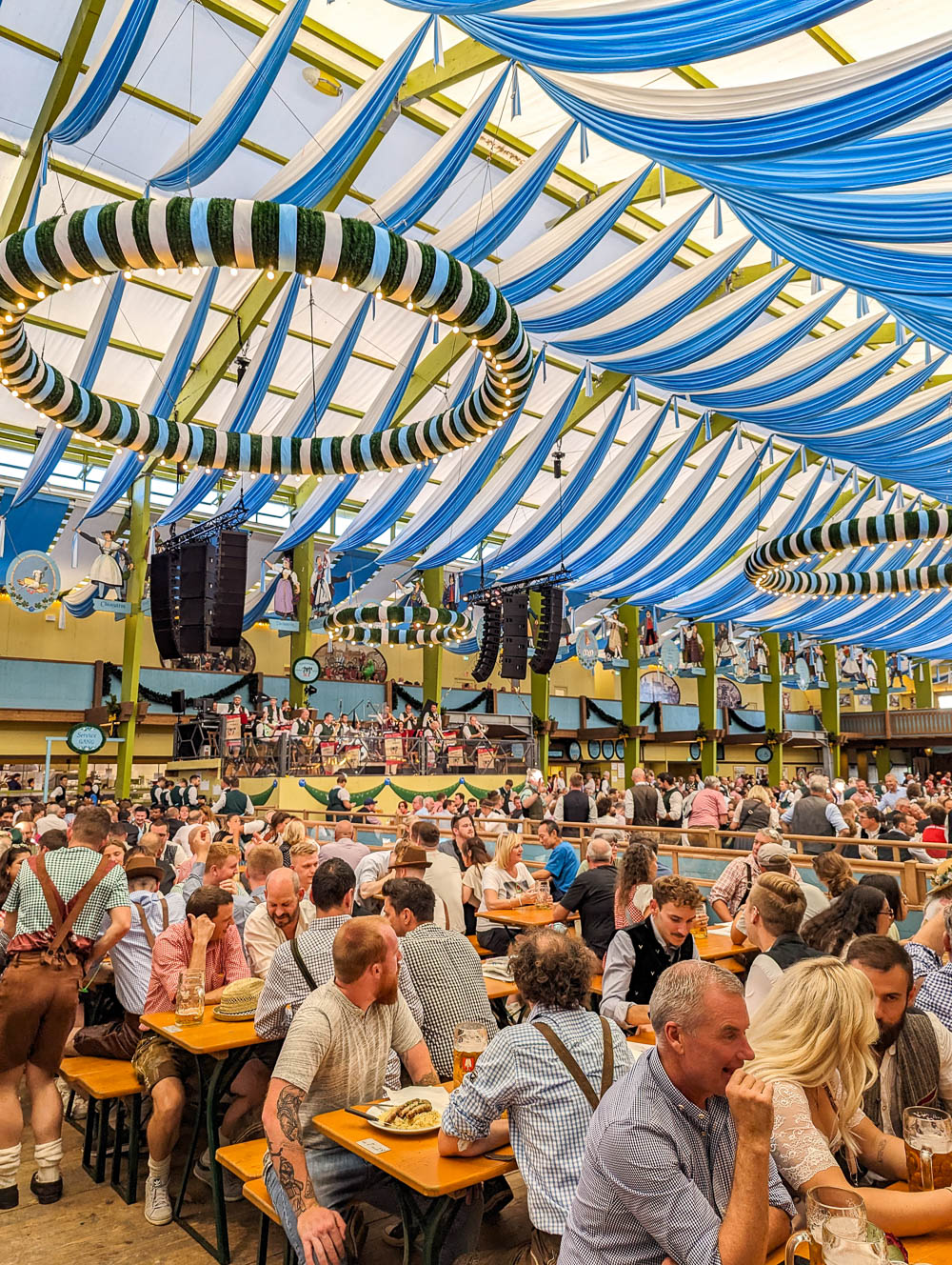 large beer tent with blue and white streamers hanging on the ceiling and filled with people