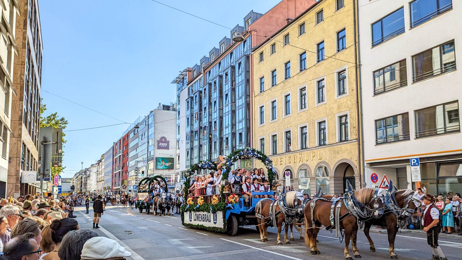 horse-drawn carriage going down a city street lined with people and colorful buildings