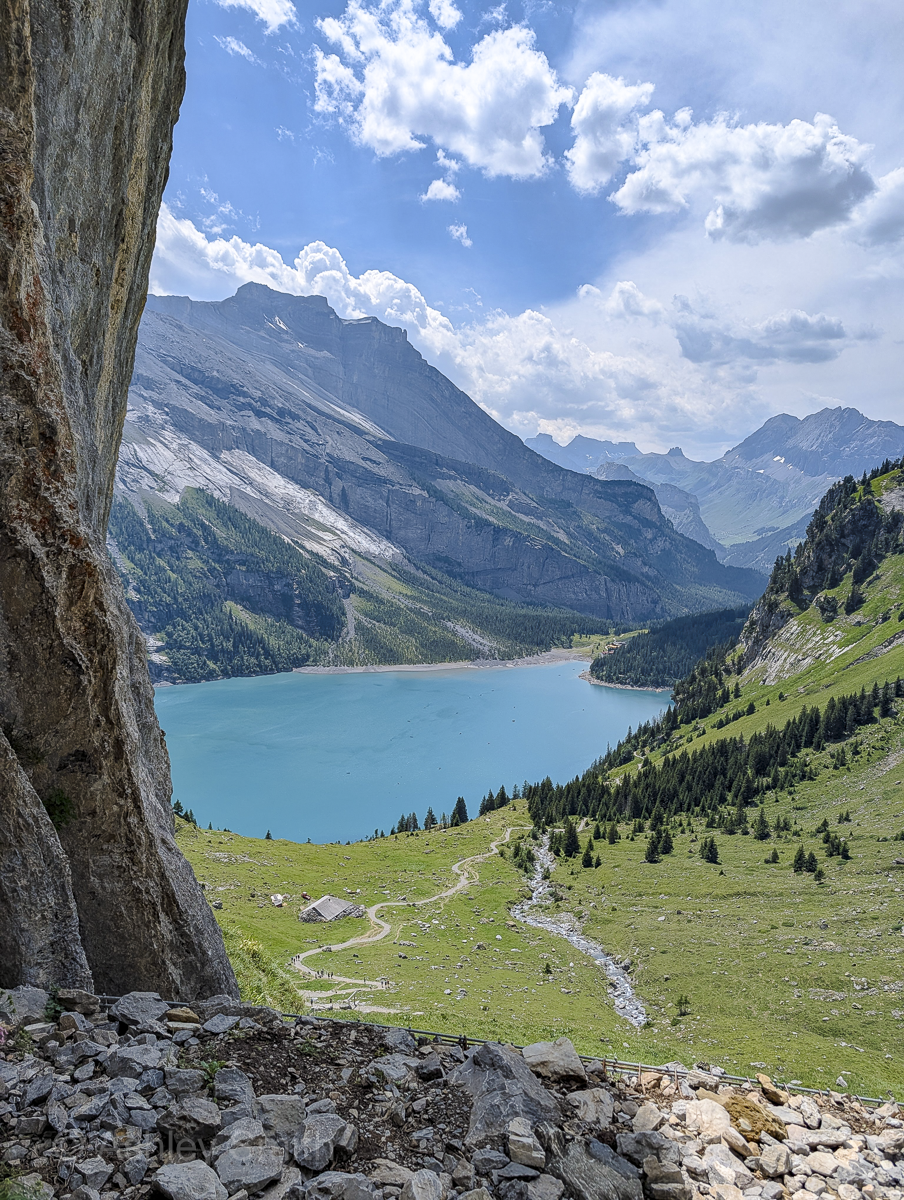 turquoise lake surrounded by green meadows and snowy mountains