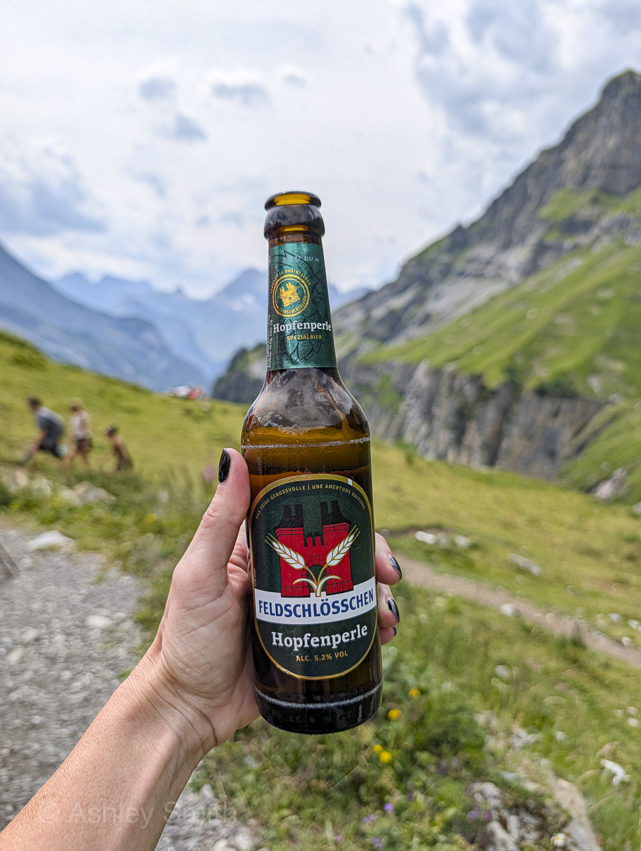 woman holding a Swiss beer in the mountains