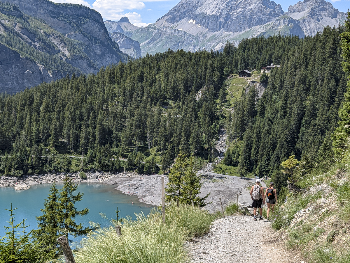 turquoise lake surrounded by green meadows and snowy mountains