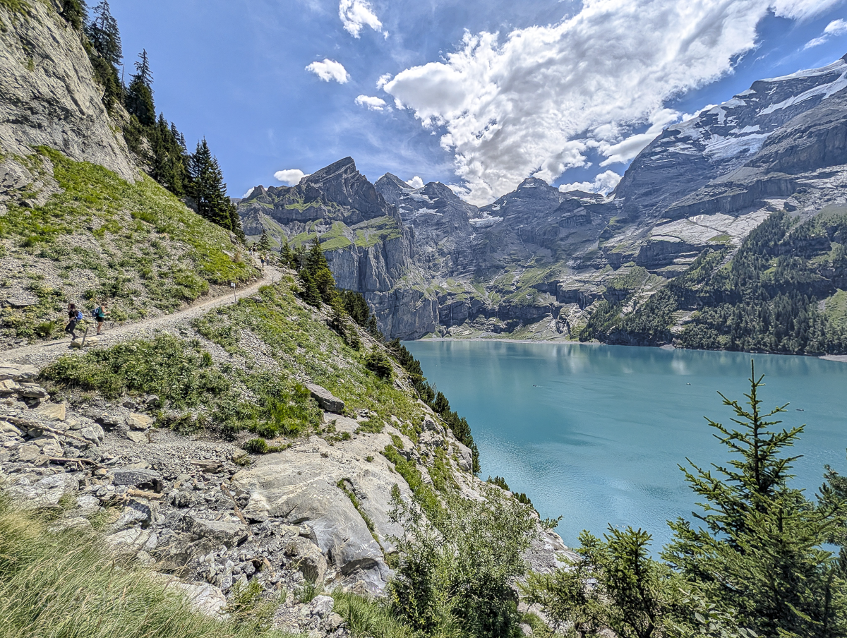 turquoise lake surrounded by green meadows and snowy mountains